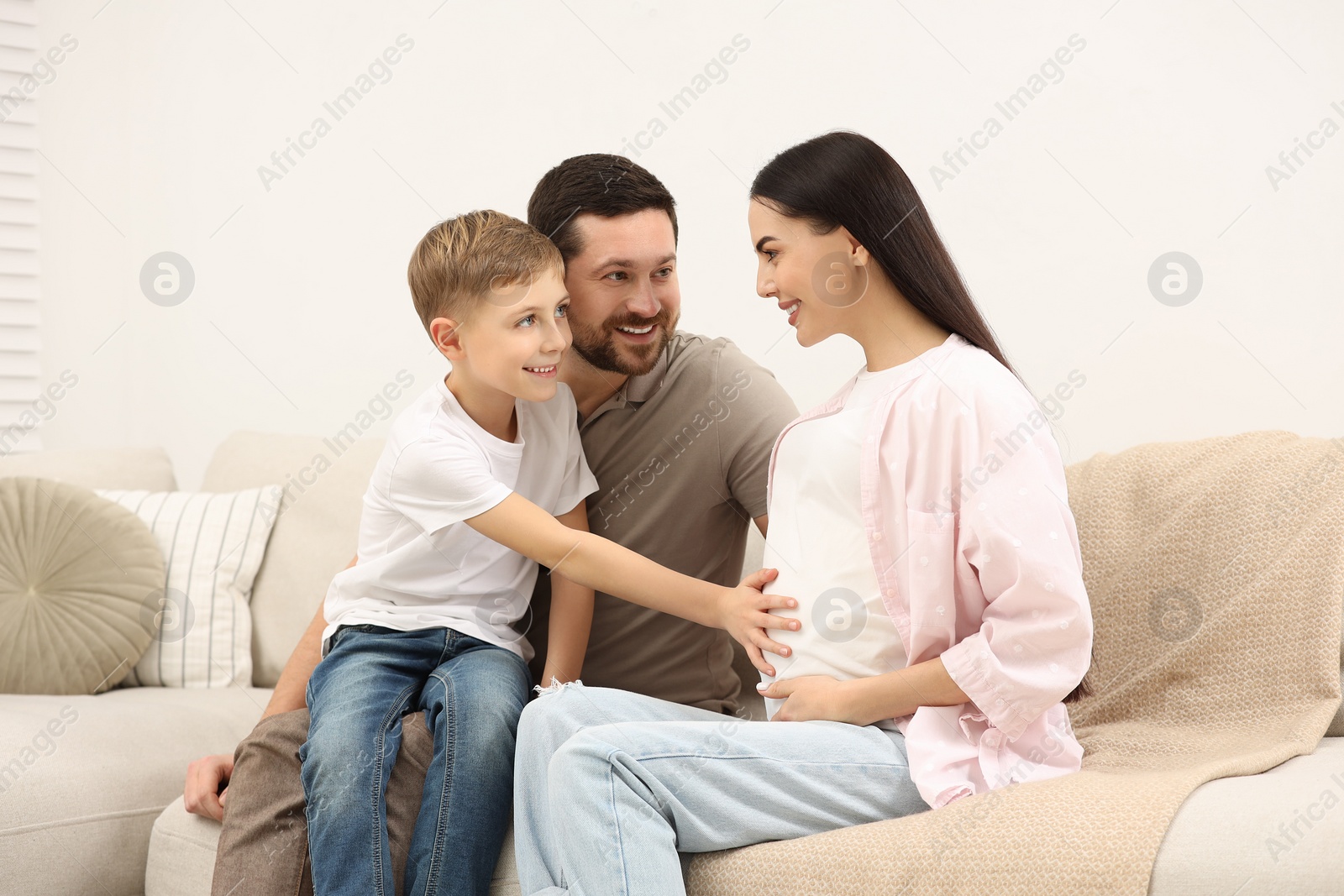 Photo of Happy pregnant woman spending time with her son and husband at home