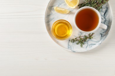Photo of Aromatic herbal tea with thyme, honey and lemons on white wooden table, top view. Space for text