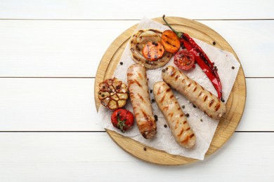 Photo of Tasty grilled sausages with vegetables on white wooden table, top view. Space for text