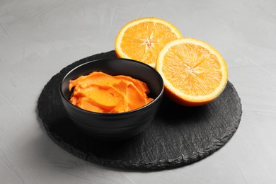 Photo of Bowl of cream painted with natural food coloring and orange on light table