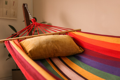 Photo of Colorful hammock with soft pillow indoors, closeup