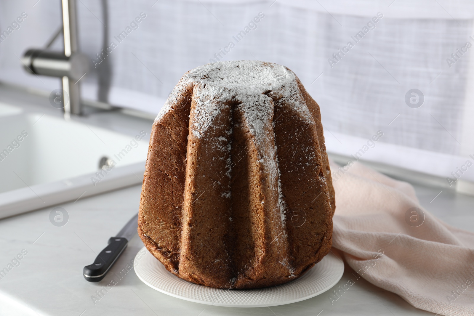 Photo of Delicious Pandoro cake decorated with powdered sugar on countertop. Traditional Italian pastry