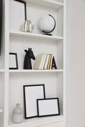 Books and different decorative elements on shelving unit indoors