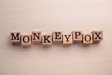 Photo of Word Monkeypox made of cubes on wooden table, top view