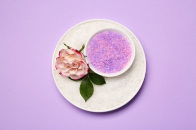 Aromatic sea salt and beautiful flower on purple background, top view