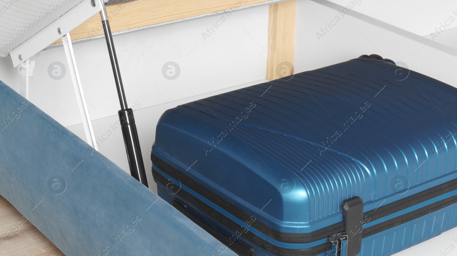 Photo of Storage drawer under bed with blue suitcase indoors