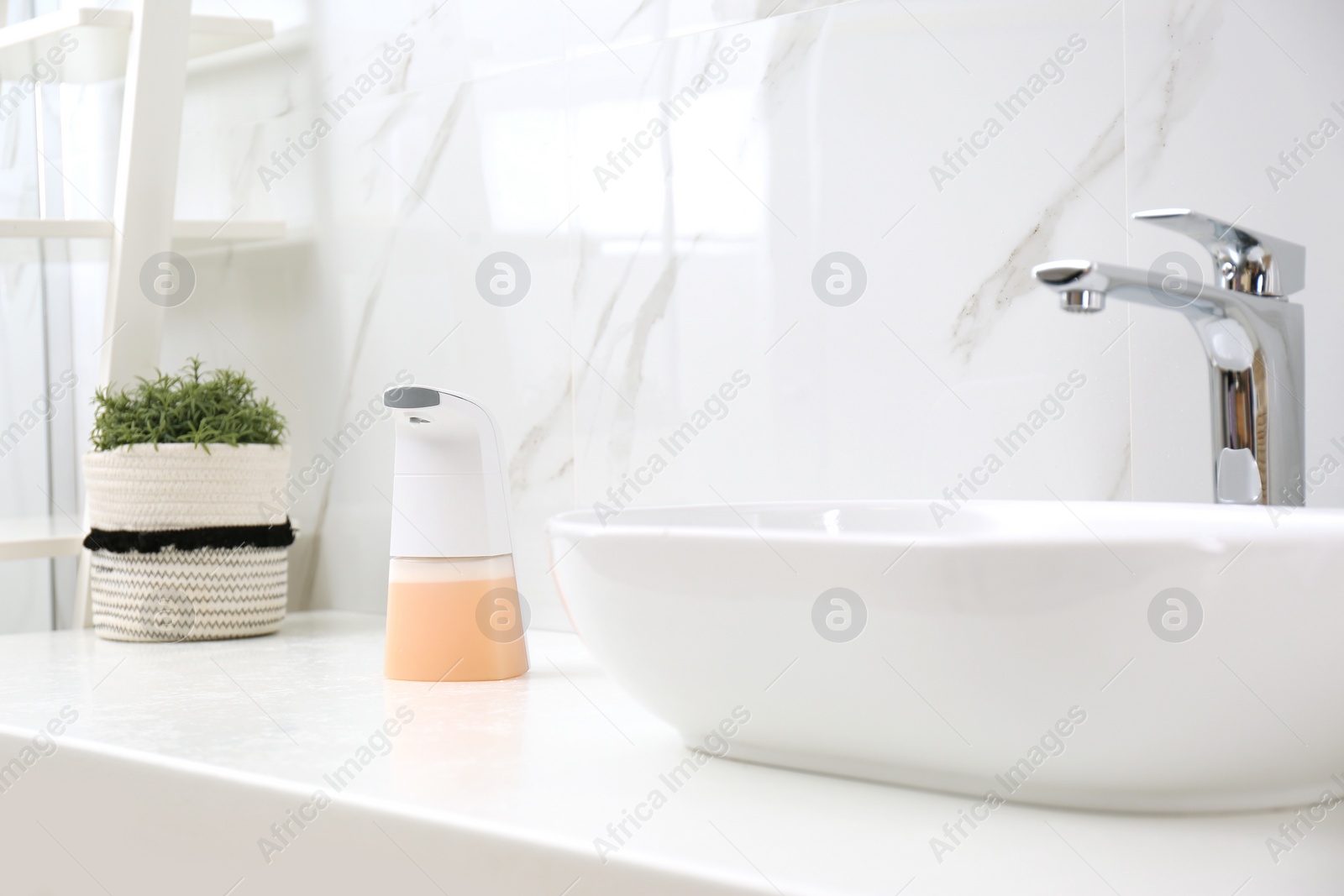 Photo of Modern automatic soap dispenser near sink in bathroom
