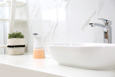 Modern automatic soap dispenser near sink in bathroom