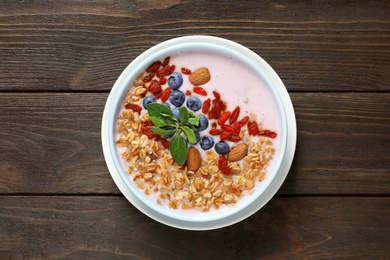 Photo of Smoothie bowl with goji berries on wooden table, top view