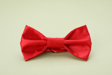 Photo of Stylish red bow tie on pale green background