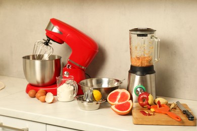 Photo of Modern red stand mixer, blender and different ingredients on white marble countertop in kitchen