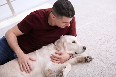 Photo of Handsome man with dog lying on carpet at home