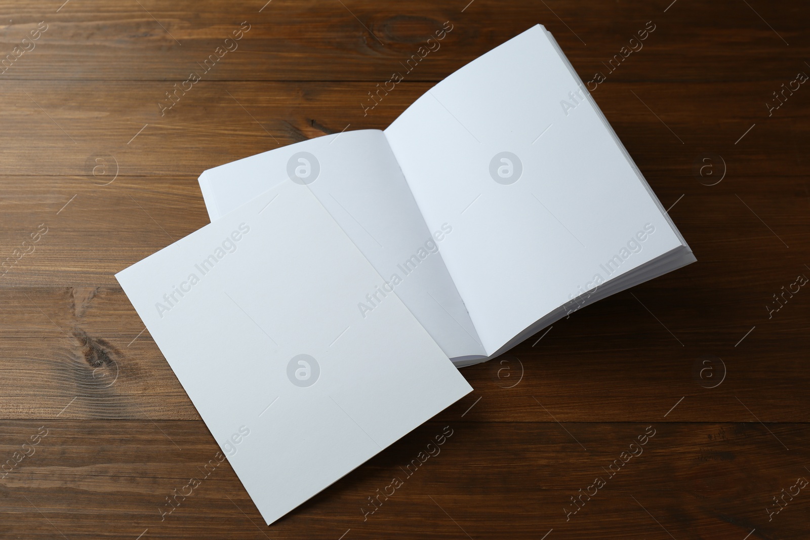 Photo of Sheet of paper and blank brochure on wooden table. Mockup for design