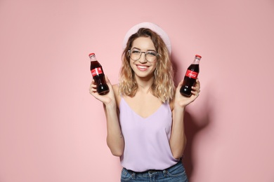 MYKOLAIV, UKRAINE - NOVEMBER 28, 2018: Young woman with bottles of Coca-Cola on color background