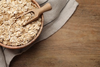 Photo of Bowl and scoop with oatmeal on wooden table, top view. Space for text