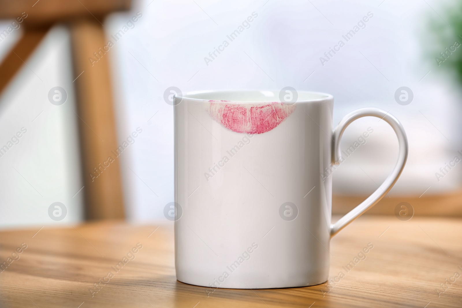 Photo of Ceramic cup with lipstick mark on table indoors