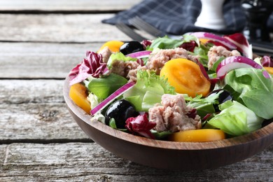 Photo of Bowl of delicious salad with canned tuna and vegetables on wooden table, space for text