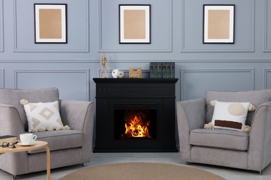 Photo of Black stylish fireplace near comfortable armchairs in cosy living room
