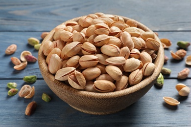 Photo of Organic pistachio nuts in bowl on wooden table