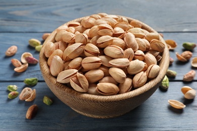 Organic pistachio nuts in bowl on wooden table