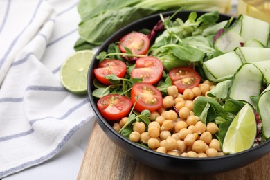 Photo of Tasty salad with chickpeas, cherry tomatoes and cucumbers on table, closeup. Space for text