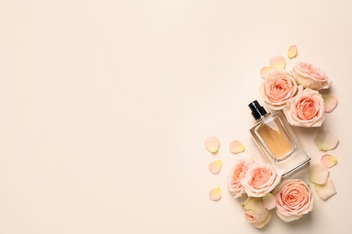 Photo of Flat lay composition with bottle of perfume and roses on light background, space for text