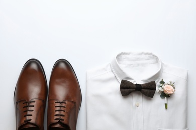 Photo of Wedding shoes and shirt on white background, top view