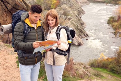 Photo of Couple of travelers with backpacks and map planning trip in mountains. Autumn vacation