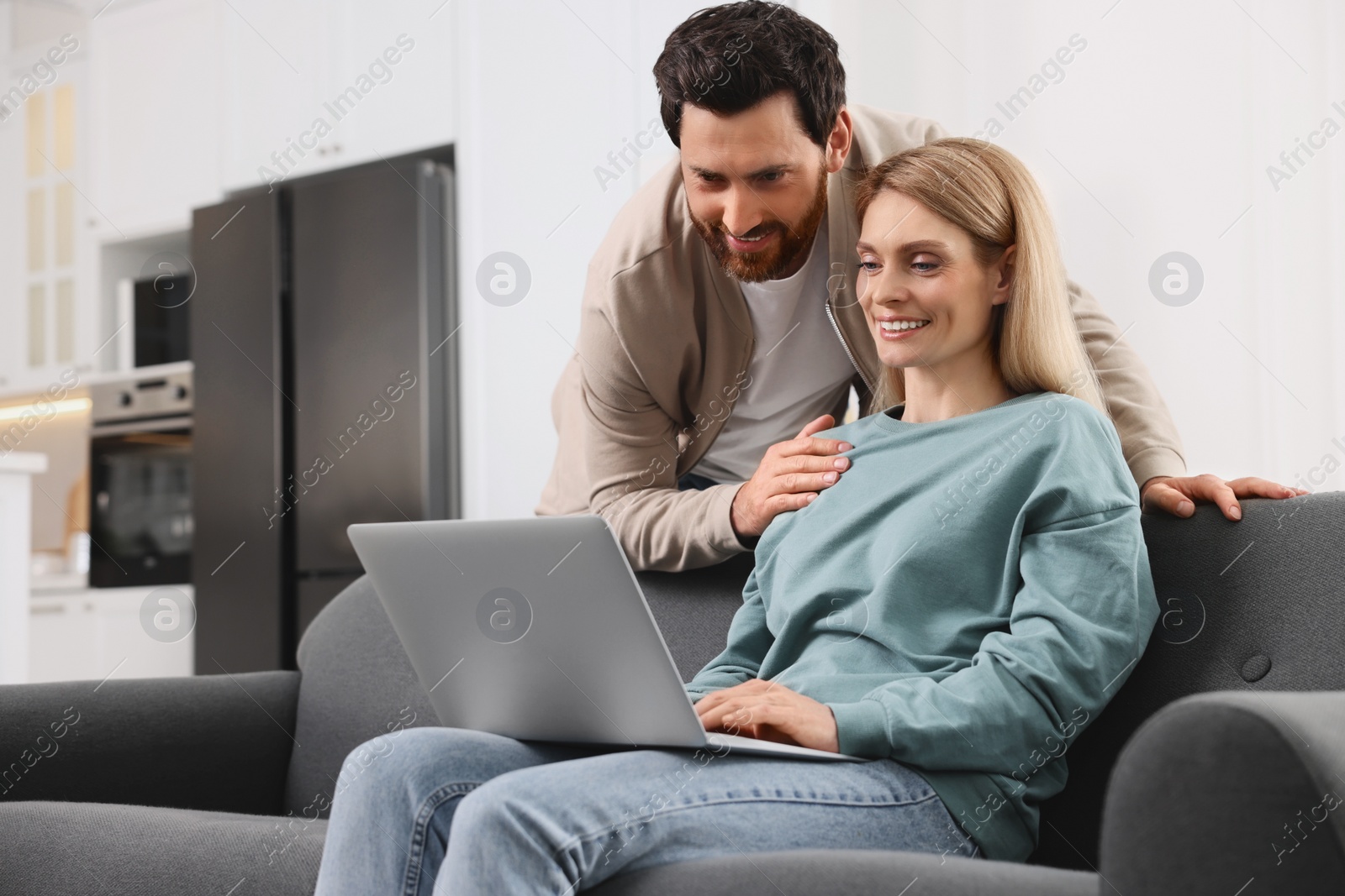 Photo of Happy couple with laptop on sofa at home