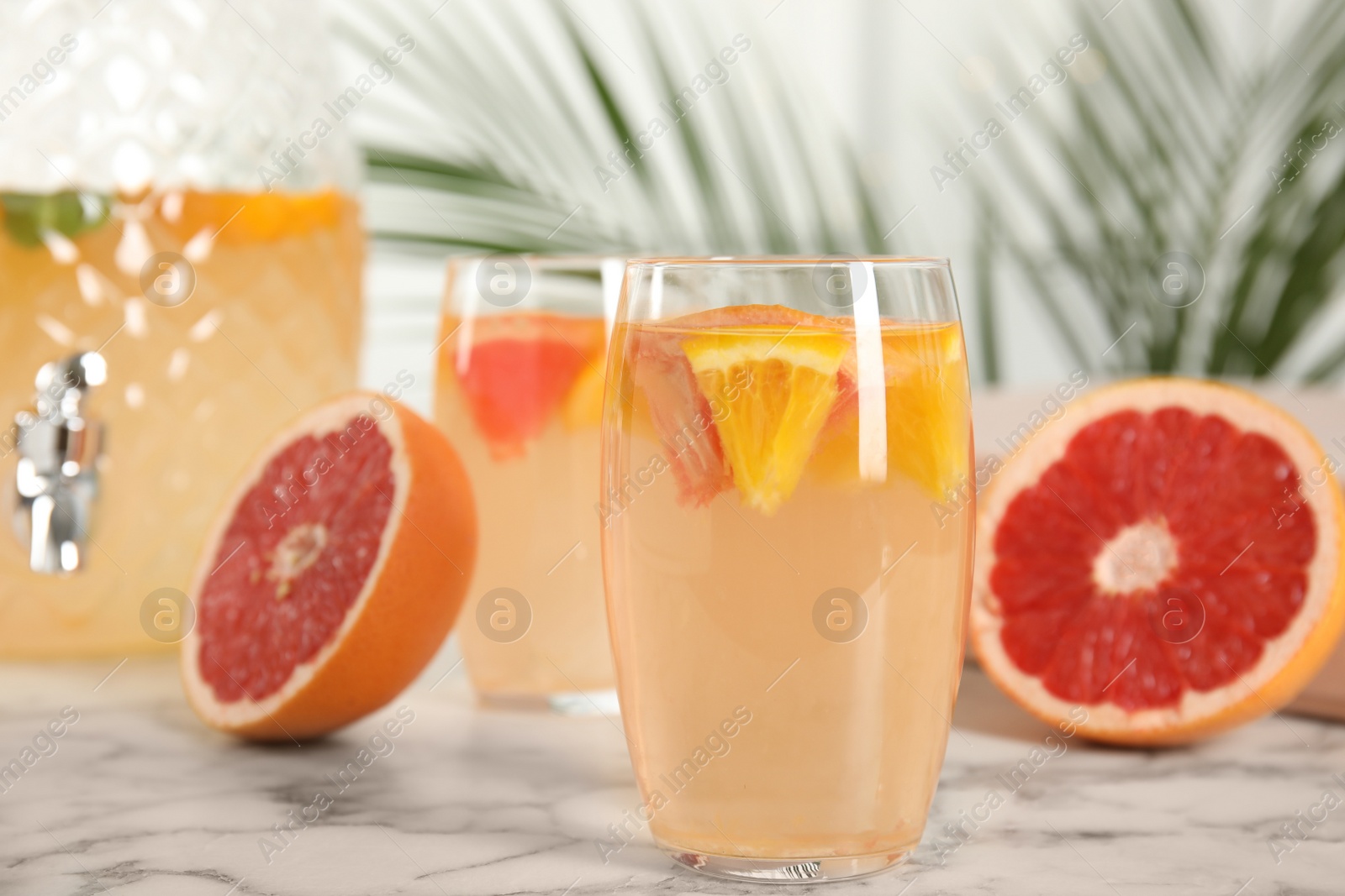 Photo of Delicious refreshing drink with orange and grapefruit on white marble table