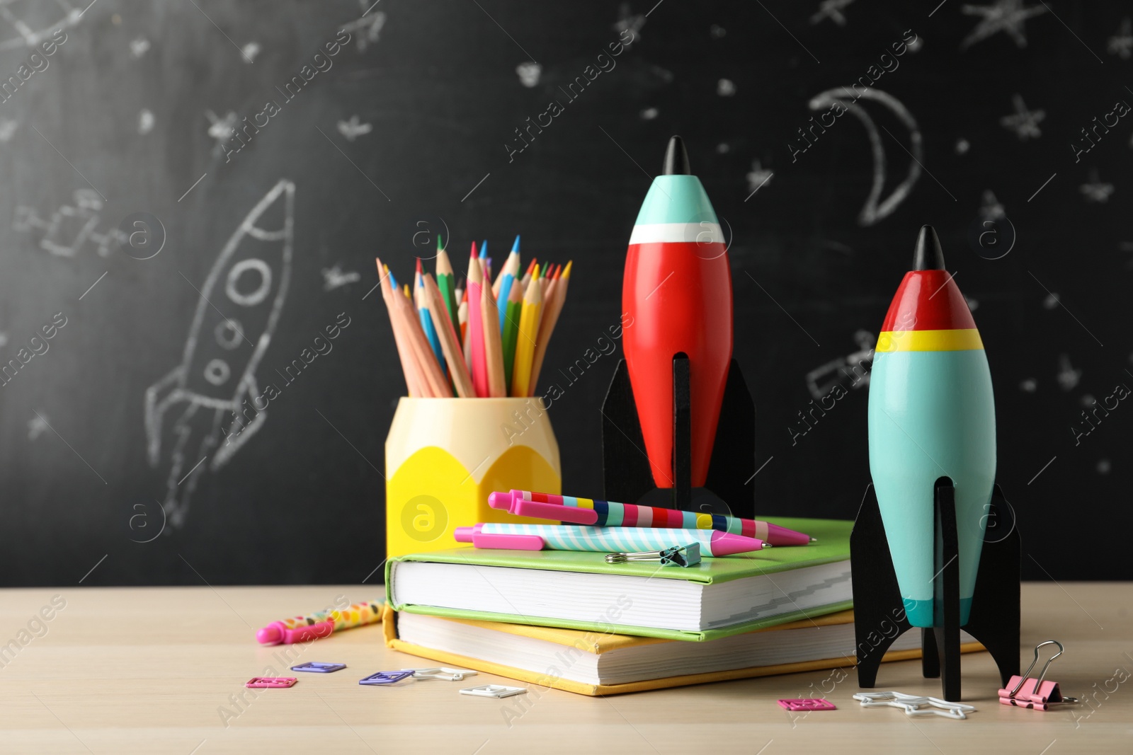 Photo of Bright toy rockets and school supplies on wooden table