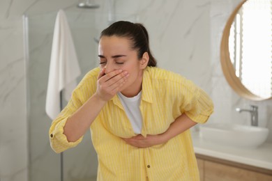 Photo of Young woman suffering from nausea in bathroom. Food poisoning