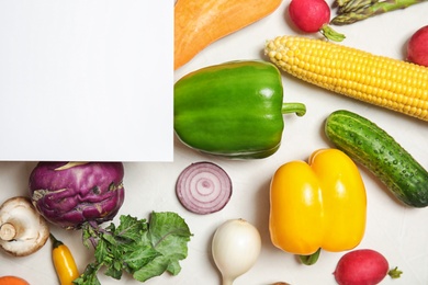 Photo of Flat lay composition with fresh vegetables and blank card for text on light background