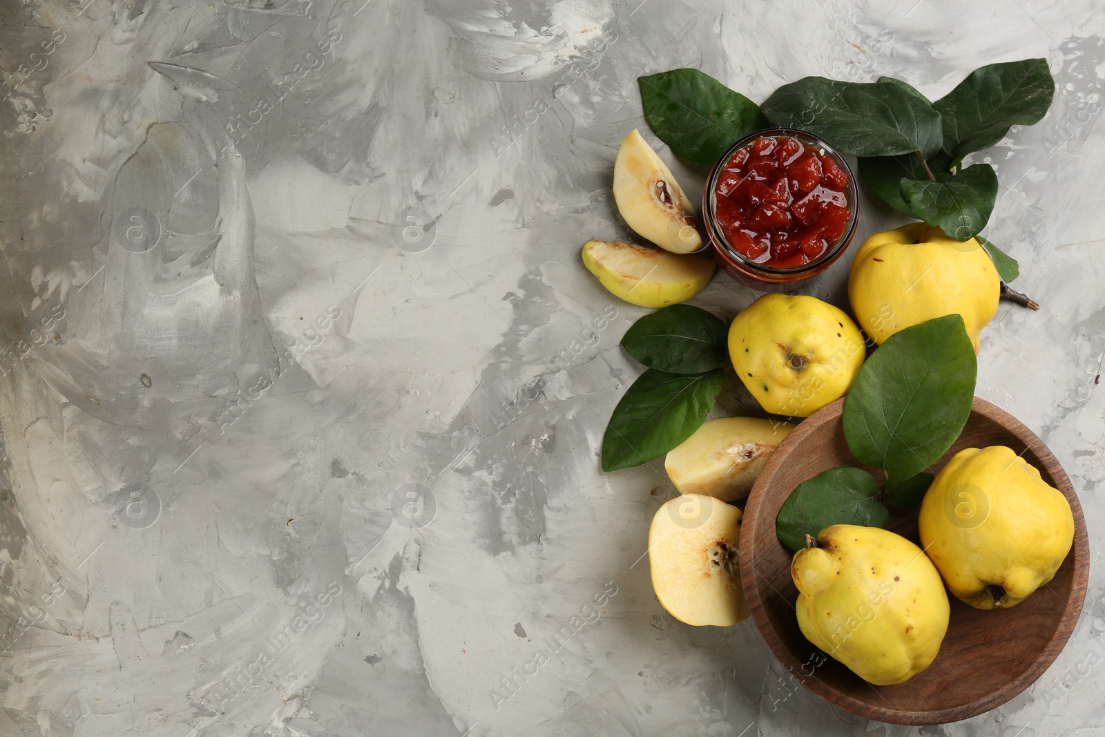 Photo of Delicious quince jam and fruits on light grey table, flat lay. Space for text