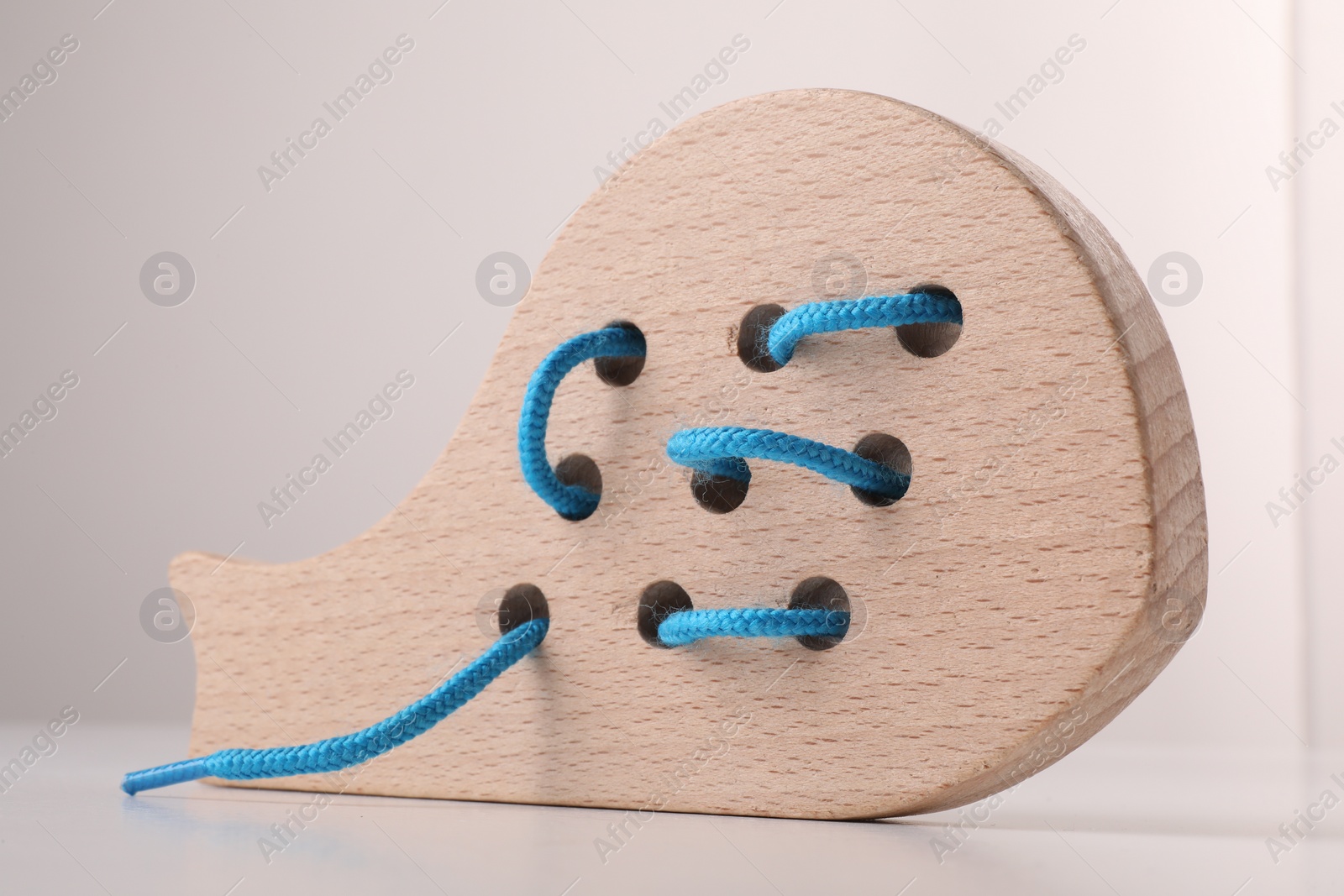 Photo of Motor skills development. Wooden lacing toy on white table, closeup