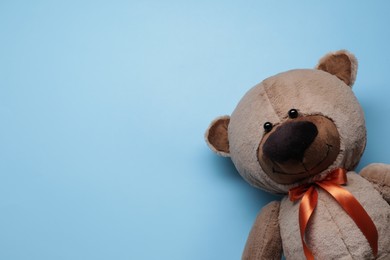 Cute teddy bear on light blue background, top view. Space for text