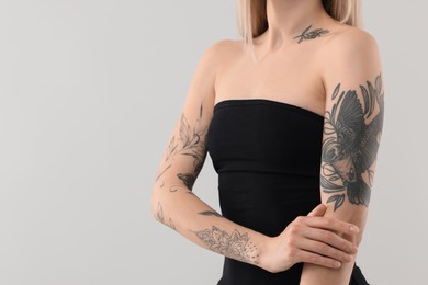 Photo of Woman with cool tattoos on light background, closeup