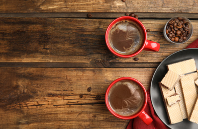 Photo of Breakfast with delicious wafers and coffee on wooden table, flat lay. Space for text