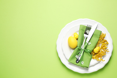 Photo of Festive Easter table setting with floral decor on green background, top view. Space for text