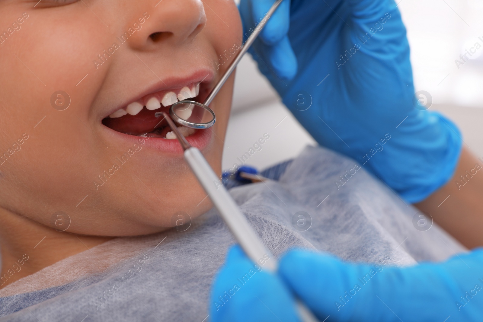 Photo of Dentist examining little boy's teeth in modern clinic, closeup