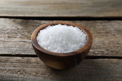 Photo of Organic salt in bowl on wooden table, closeup