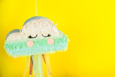 Photo of Cloud shaped pinata hanging on yellow background. Space for text