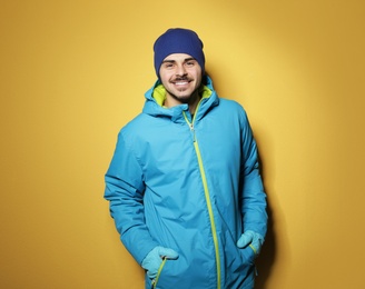 Photo of Young man wearing warm clothes on color background. Ready for winter vacation