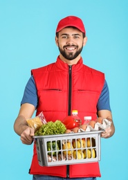 Photo of Man holding basket with fresh products on color background. Food delivery service