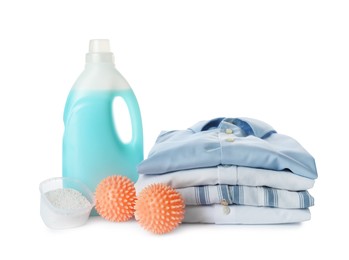 Photo of Orange dryer balls, detergents and stacked clean clothes on white background