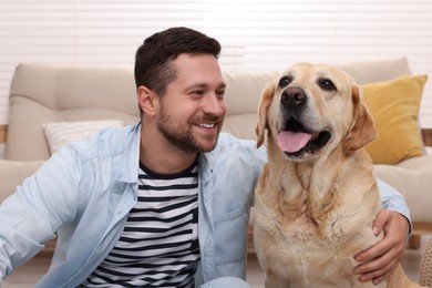 Photo of Man hugging with adorable Labrador Retriever dog at home. Lovely pet