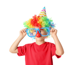 Photo of Little boy in clown wig, party hat and funny glasses on white background. April fool's day