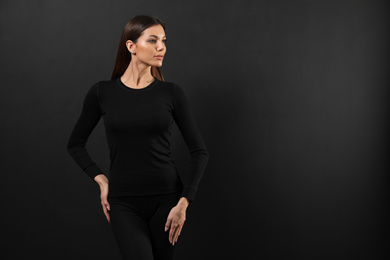 Woman wearing thermal underwear on black background. Space for text