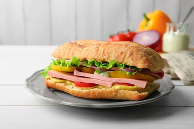 Photo of Tasty sandwich with boiled sausage, cheese and vegetables on white wooden table