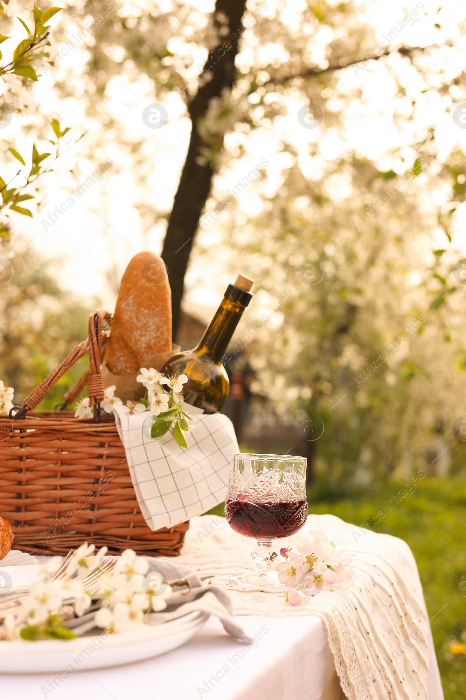 Photo of Stylish table setting with beautiful spring flowers and wine in garden